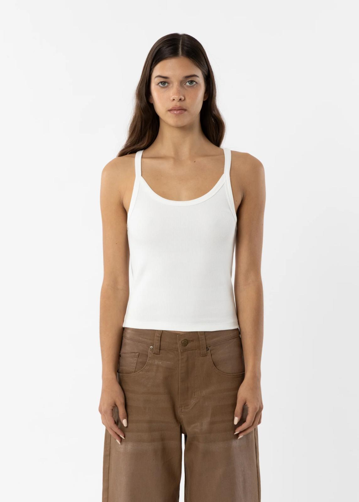 Woman wearing a white tank top and brown pants on a white background
