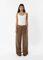 Woman wearing a white tank top and brown pants on a white background